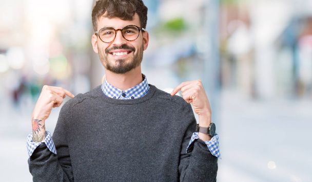 Mladý pohledný inteligentní muž nosí brýle izolované pozadí sebevědomým úsměvem na tváři, polohovací sebe prsty hrdý a šťastný. - Fotografie, Obrázek