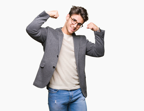 Jovem homem de negócios usando óculos sobre fundo isolado mostrando os músculos dos braços sorrindo orgulhoso. Conceito de aptidão
. - Foto, Imagem