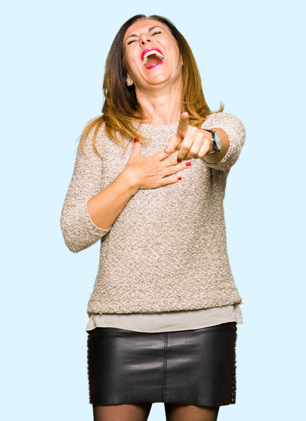 Piękny wiek średni kobieta moda swetrze rozweselający u, wskazując na aparat z palca ręki na klatce piersiowej, wstyd wyrażenie - Zdjęcie, obraz