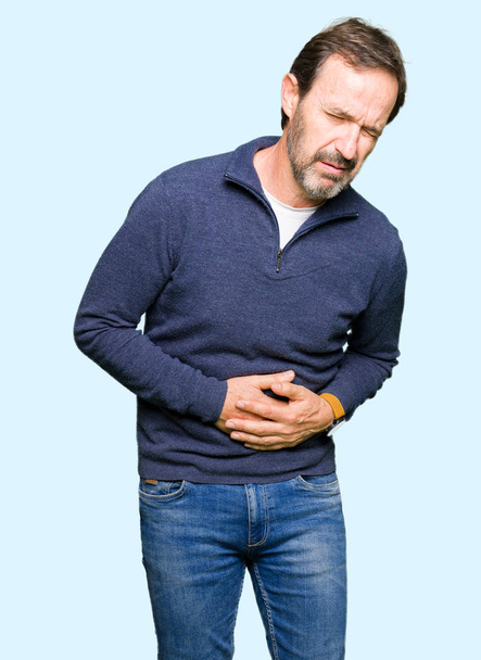 Middle age handsome man wearing a sweater with hand on stomach because nausea, painful disease feeling unwell. Ache concept. - Photo, Image