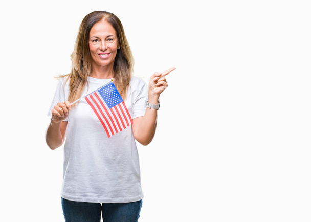 Middle age hispanic woman holding flag of United States of America over isolated background very happy pointing with hand and finger to the side - Valokuva, kuva
