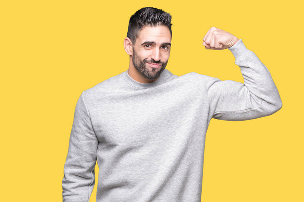 Jovem homem bonito vestindo camisola sobre fundo isolado Pessoa forte mostrando músculo do braço, confiante e orgulhoso do poder
 - Foto, Imagem