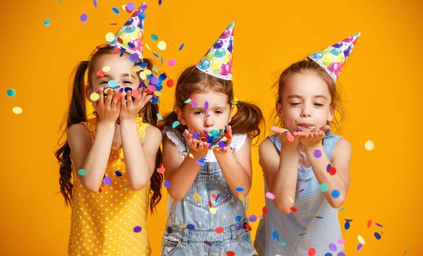 feliz aniversário crianças meninas com confete no backgroun amarelo colorido
 - Foto, Imagem