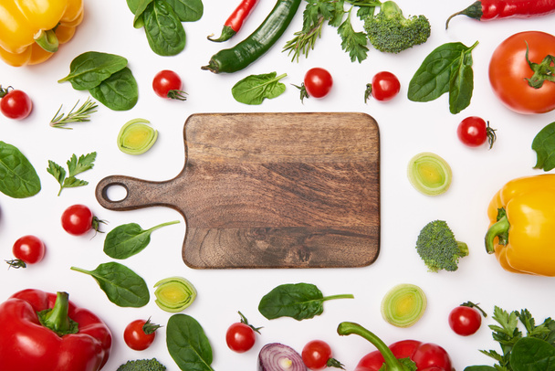Flat lay with wooden cutting board and natural vegetables on white background - Foto, Imagen