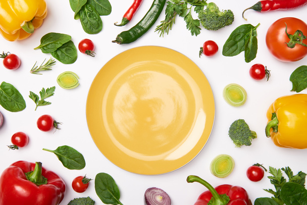 flache Lage mit gelbem Teller und Gemüse auf weißem Hintergrund - Foto, Bild