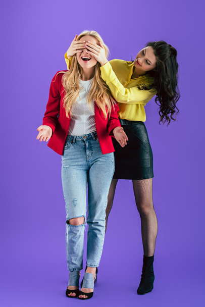 Two stylish girls fooling around on purple background - Foto, afbeelding