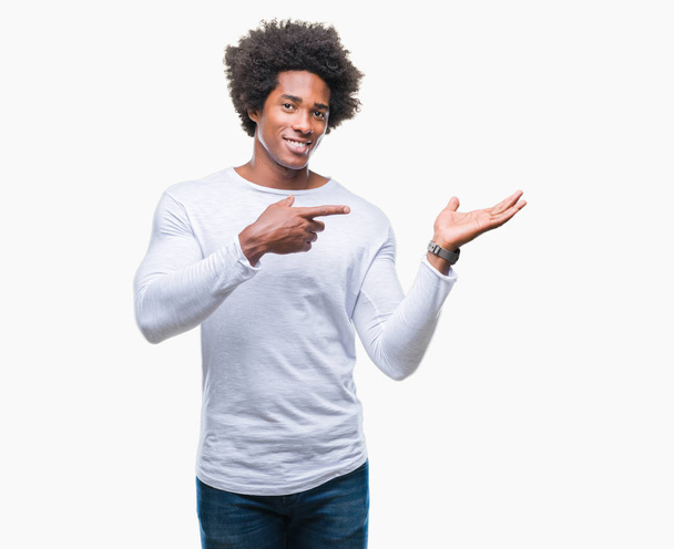 Afro Αμερικανός άνθρωπος πάνω από απομονωμένη φόντο έκπληκτος και χαμογελώντας στην κάμερα, ενώ παρουσιάζει με το χέρι και δείχνοντας με το δάχτυλο. - Φωτογραφία, εικόνα