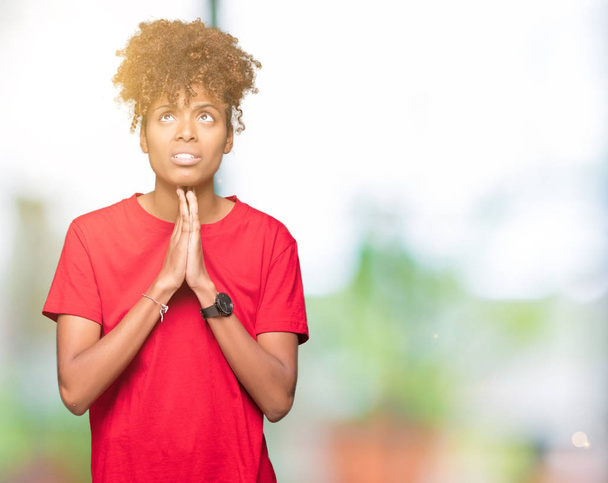 Όμορφη νεαρή αφρικανική αμερικανική γυναίκα πέρα από το απομονωμένο υπόβαθρο επαιτεία και προσεύχεται με τα χέρια μαζί με ελπίδα έκφραση προσώπου πολύ συναισθηματική και ανησυχούν. Ζητώντας συγχώρεση. Έννοια της θρησκείας. - Φωτογραφία, εικόνα