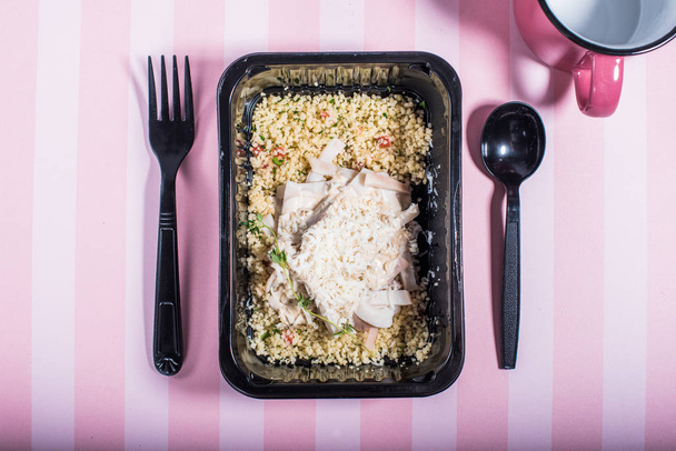 Cuscus garnish with meat in plastic container on striped pink background - Valokuva, kuva