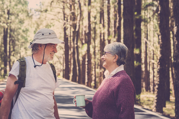 Velho casal caucasiano sorrir e desfrutar durante a viagem na floresta pinheiros em montanhas
 - Foto, Imagem