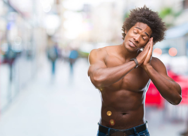 Afro americano uomo senza maglietta mostrando corpo nudo su sfondo isolato sonno stanco sognare e posa con le mani insieme sorridendo con gli occhi chiusi
. - Foto, immagini