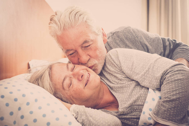 Caucasian man kissing woman in early morning at bed  - Photo, image