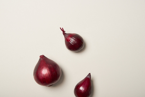 Vista superior de tres cebollas rojas sobre fondo gris
 - Foto, Imagen