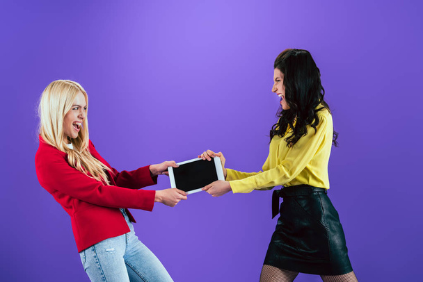 女の子の悲鳴と紫色の背景に空白の画面を持つデジタル タブレットのために戦って - 写真・画像