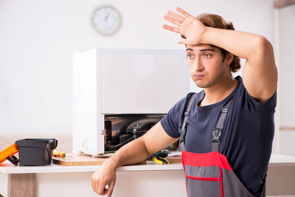 Jeune entrepreneur beau réparer réfrigérateur
  - Photo, image