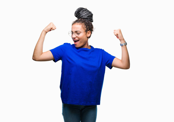 Genç gururlu gülümseyen kol kasları gösterilen izole arka plan üzerinde gözlük saç Afro-Amerikan Kız örgülü. Fitness kavramı. - Fotoğraf, Görsel