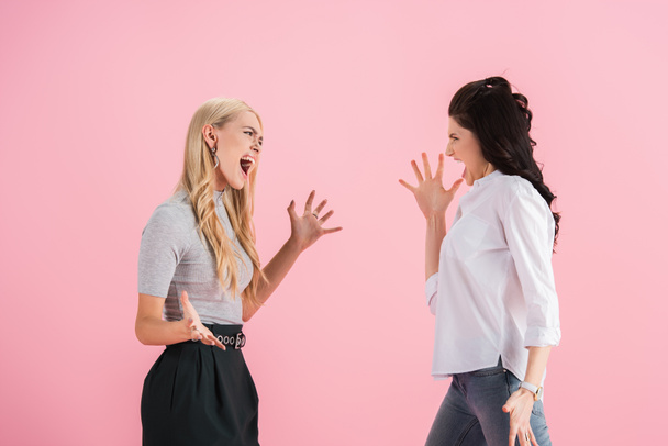 Aggressive girls screaming at each other and waving hands isolated on pink - Foto, afbeelding