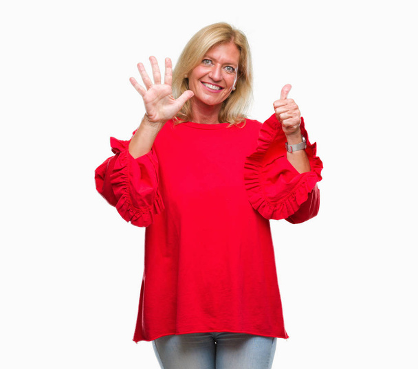 Μέσης ηλικίας ξανθιά γυναίκα απομονωμένη φόντο δείχνει και δείχνει προς τα επάνω με τα δάχτυλα αριθμός έξι ενώ χαμογελώντας αυτοπεποίθηση και χαρούμενοι. - Φωτογραφία, εικόνα