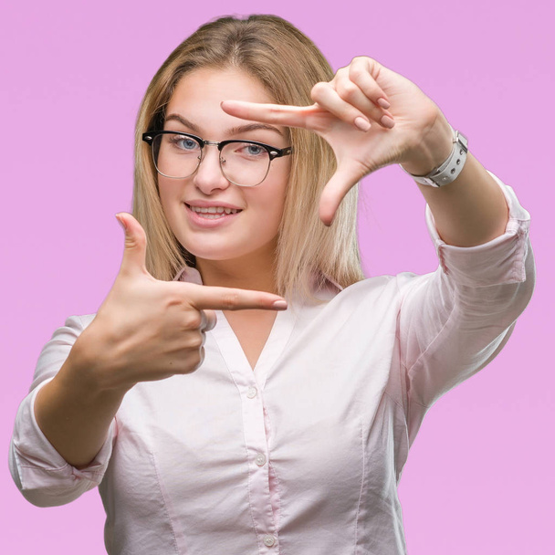 Giovane donna d'affari caucasica indossa occhiali su sfondo isolato sorridente rendendo cornice con le mani e le dita con il viso felice. Creatività e concetto di fotografia
. - Foto, immagini