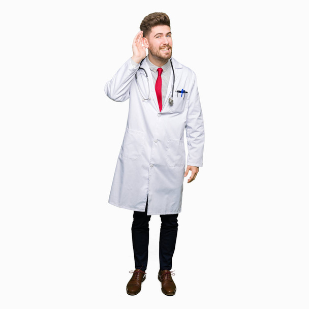 若いハンサムな医者の噂やゴシップに審理をリスニングの耳に手を浮かべて医療のコートを着た男。難聴の概念. - 写真・画像