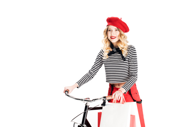szép nő a gazdaság bevásárló táskák közelében kerékpár elszigetelt fehér piros beret  - Fotó, kép