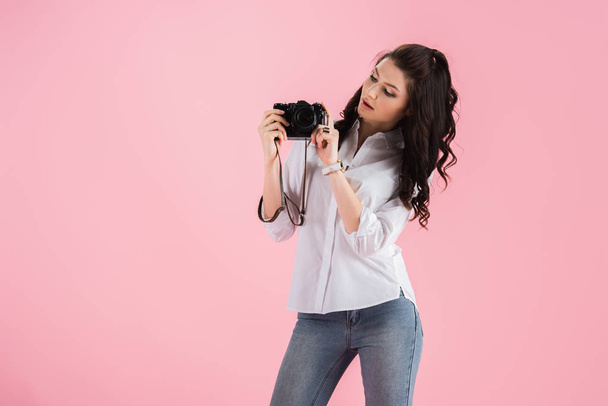 ピンクに分離されたデジタル カメラと好奇心若い女性のスタジオ撮影 - 写真・画像