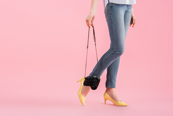 Cropped view of woman in yellow shoes holding digital camera on pink background - Valokuva, kuva