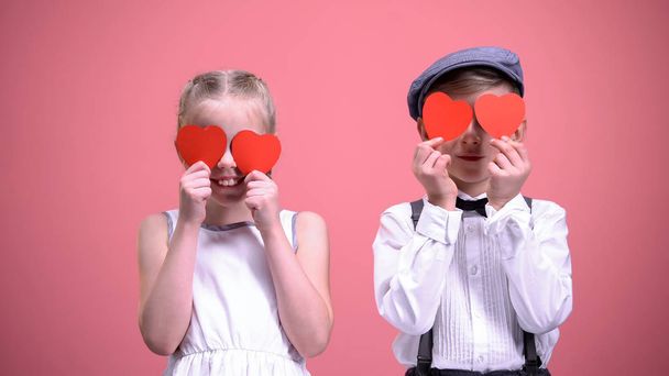 Little boy and girl closing eyes with paper hearts, having fun on Valentines day - Fotoğraf, Görsel