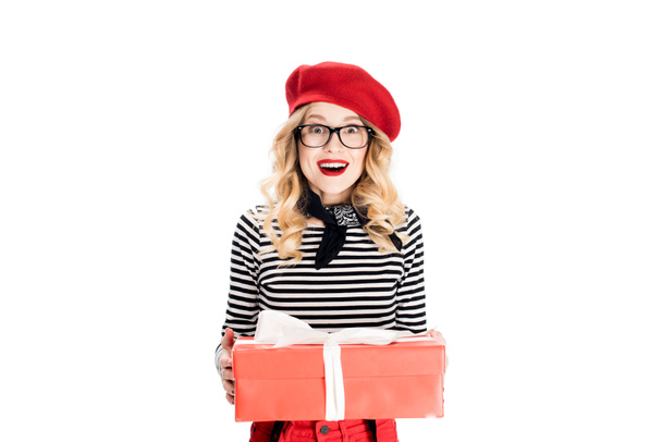 χαρούμενα ξανθιά γυναίκα στο κόκκινο μπερέ κρατώντας κουτί δώρου που απομονώνονται σε λευκό  - Φωτογραφία, εικόνα