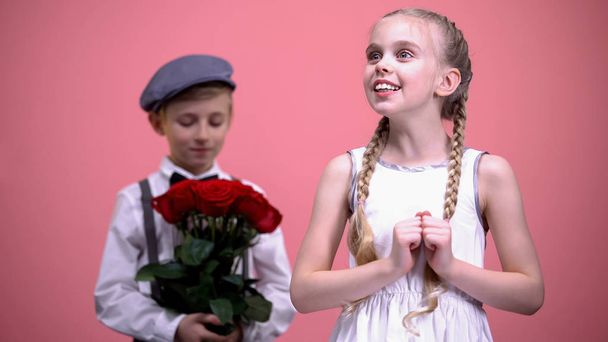 Little male ready to give red roses bouquet to little female, Valentines day - 写真・画像