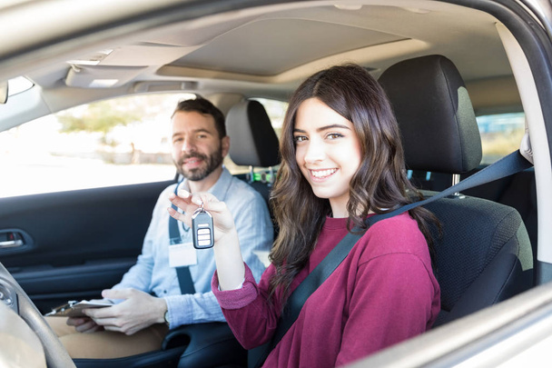 gut aussehende Frau zeigt Autoschlüssel, während der Fahrlehrer während des Kurses lächelt - Foto, Bild