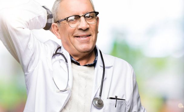 schöner Oberarzt Mann in medizinischem Mantel lächelt zuversichtlich berühren Haare mit Hand nach oben Geste, posiert attraktiv - Foto, Bild