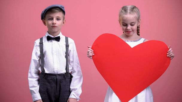 Young girl holding red paper heart, standing near young boy, Valentines day - Foto, Imagem