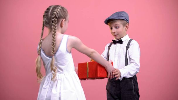 Little girl in white dress giving wrapped present to boyfriend, Valentines day - Foto, Bild