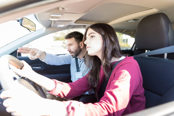 Professor de condução mostrando direção para jovem estudante durante o teste de condução
 - Foto, Imagem