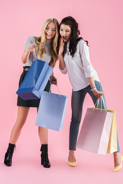 Захоплені дівчата відкривають сумки для покупок на рожевому фоні
 - Фото, зображення