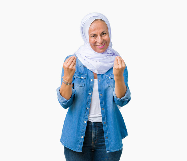 Middle age eastern arab woman wearing arabian hijab over isolated background Doing money gesture with hand, asking for salary payment, millionaire business - Fotoğraf, Görsel