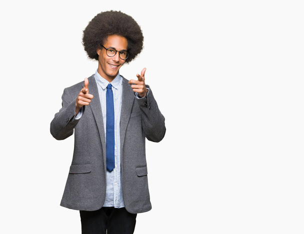 Mladí africké americké obchodní muž s afro vlasy nosí brýle, ukazují prstem na kameru s šťastný a legrační obličej. Dobrá energie a vibrace. - Fotografie, Obrázek