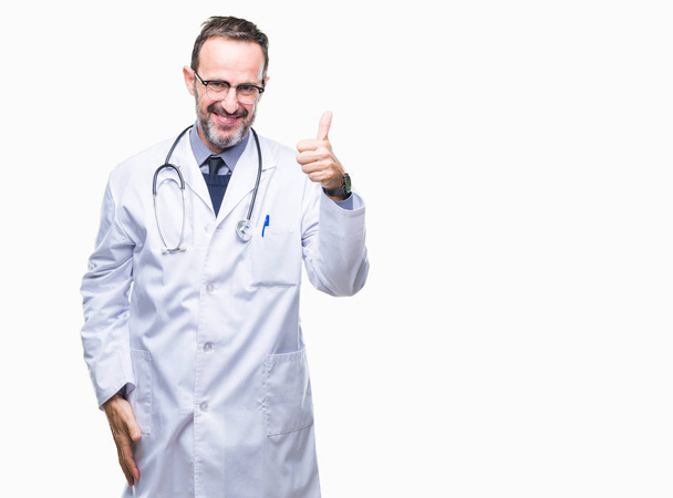 Middle age senior hoary doctor man wearing medical uniform isolated background doing happy thumbs up gesture with hand. Approving expression looking at the camera with showing success. - 写真・画像