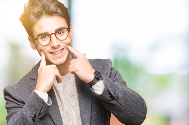 Genç iş adamı gözlük izole üzerinde gülen arka plan açık ağız ile parmak işaret ve neşeli gülümseme zorlamadan - Fotoğraf, Görsel