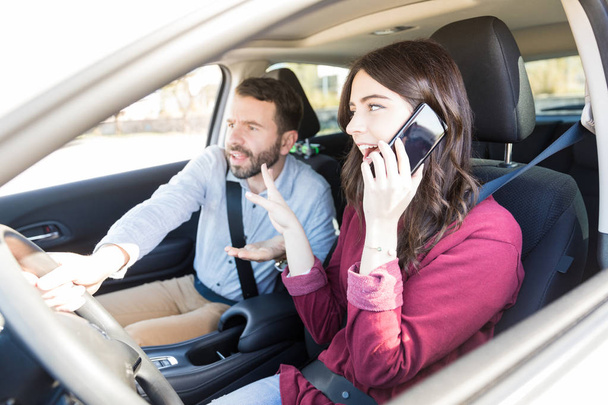 Hombre guapo toma el control del coche mientras el conductor utiliza el teléfono móvil y perder la concentración
 - Foto, imagen
