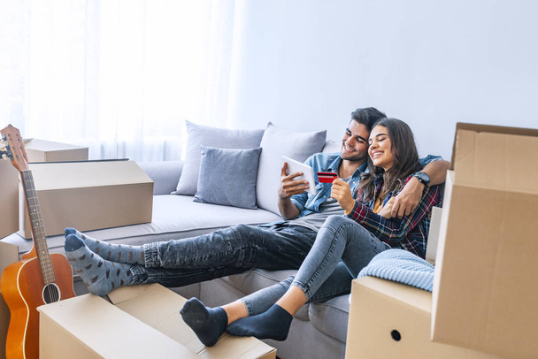 Young couple with credit card and digital tablet in new home - Foto, immagini