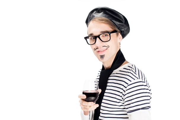 glücklicher französischer Mann hält ein Glas Wein in der Hand und lächelt isoliert auf weiß  - Foto, Bild