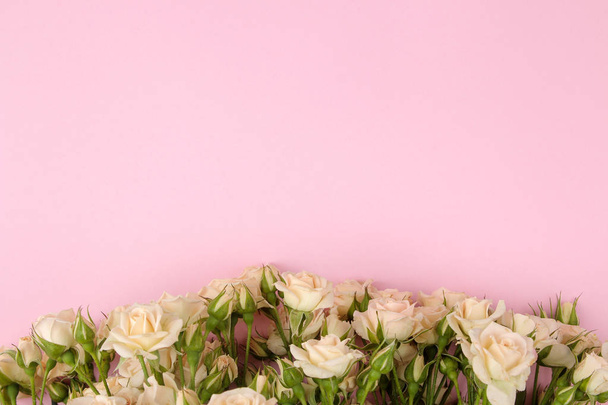 Marco de hermosas mini rosas beige sobre un fondo rosa brillante. vacaciones. lugar para el texto. vista superior
 - Foto, imagen