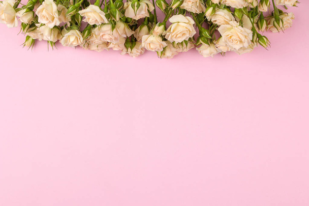 Marco de hermosas mini rosas beige sobre un fondo rosa brillante. vacaciones. lugar para el texto. vista superior
 - Foto, imagen
