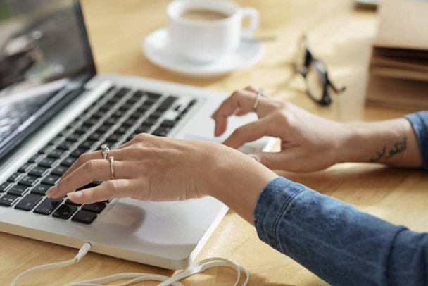 Руки жінки-підприємця, що працює на ноутбуці за її офісним столом
 - Фото, зображення