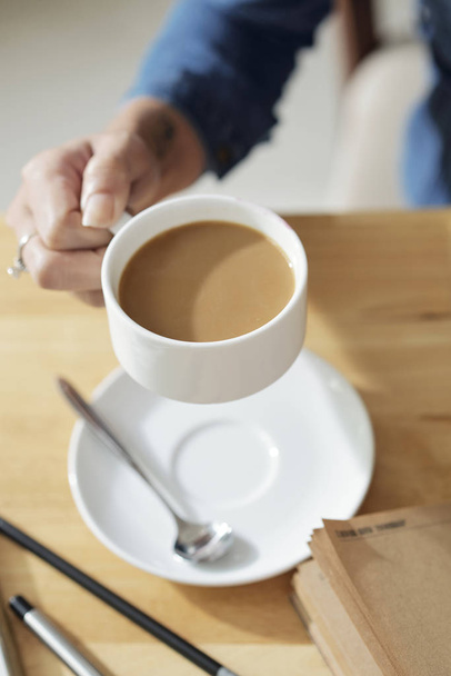 Kadın girişimci elinde süt ile lezzetli kahve - Fotoğraf, Görsel