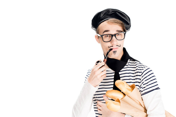 confident french man in glasses smoking pipe and holding baguettes isolated on white - Foto, imagen