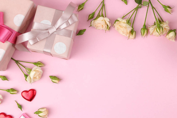 Mooie mini rozen met een roze giftdoos op een lichte roze achtergrond. vakantie. Aftelkalender voor Valentijnsdag. Dag van de vrouw. bovenaanzicht. ruimte voor tekst - Foto, afbeelding