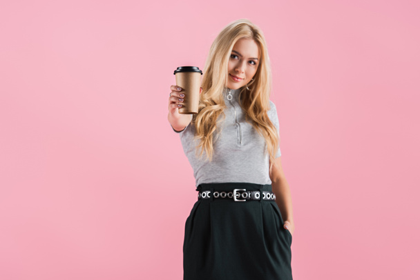 beautiful blonde girl holding disposable cup of coffee, isolated on pink - Foto, Bild